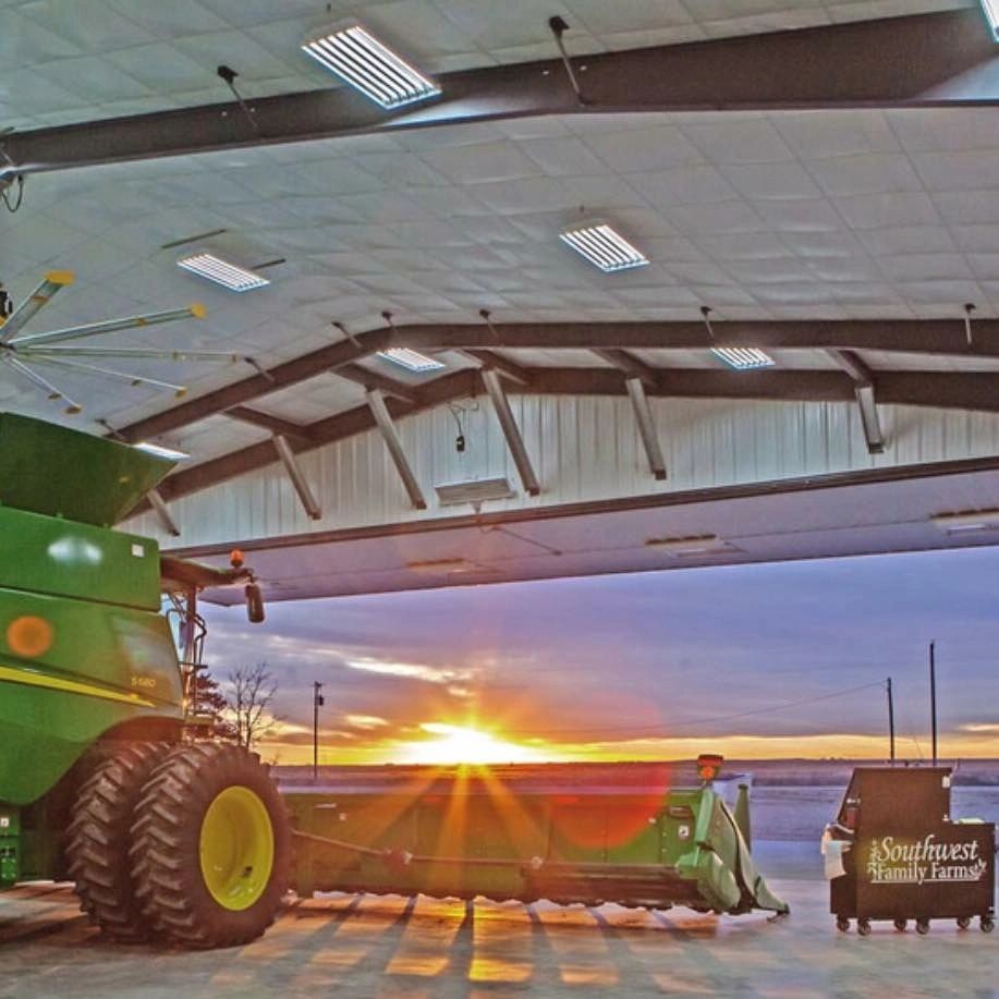 Combine harvester at barn during sunset