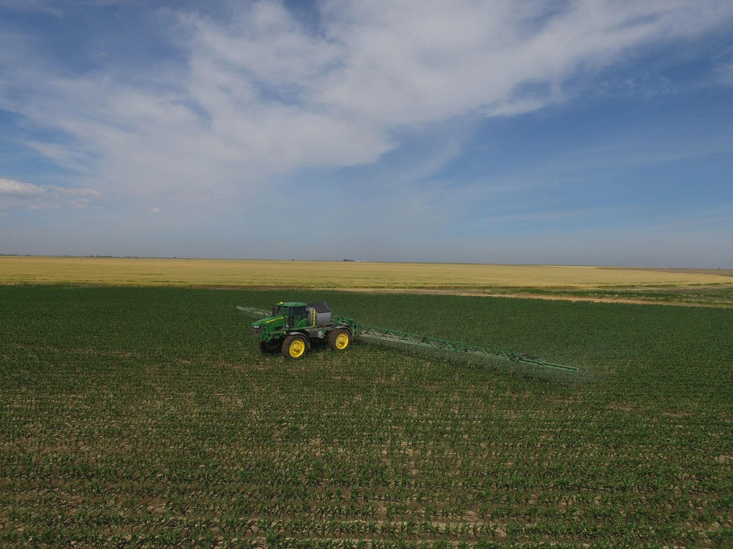 Aerial view of tractor spraying crops in field